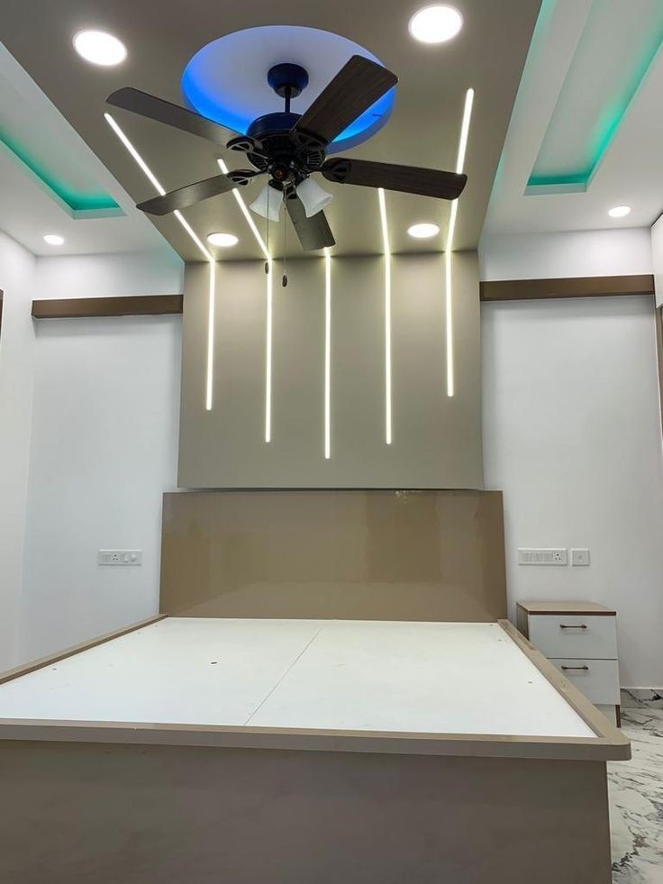 a ceiling fan in the middle of an empty room with white walls and flooring