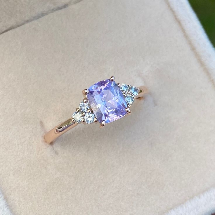 an engagement ring with a tan and blue stone surrounded by three white diamonds in a box