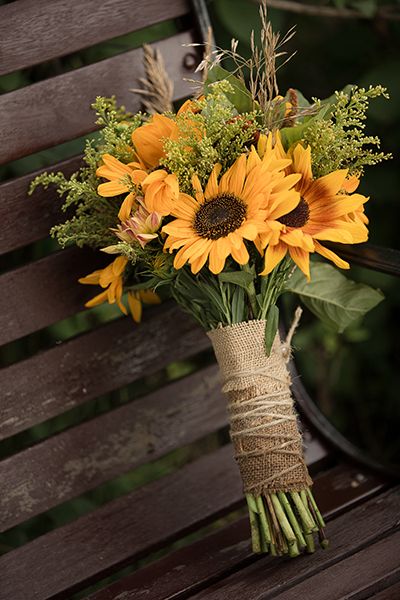 a bouquet of sunflowers tied to a bench