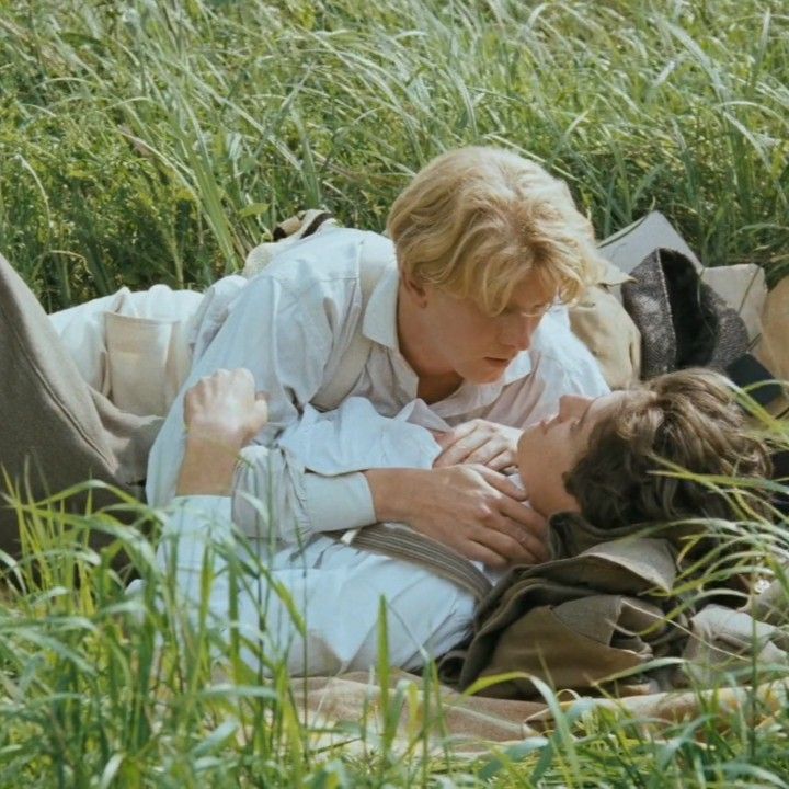 two people laying in the grass with their heads on each other's chests