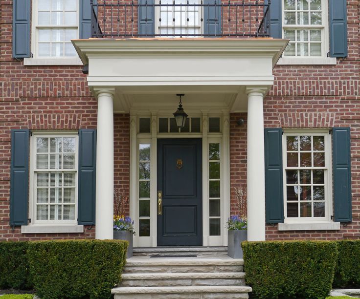 an elegant brick house with blue shutters and white pillars on the front door,