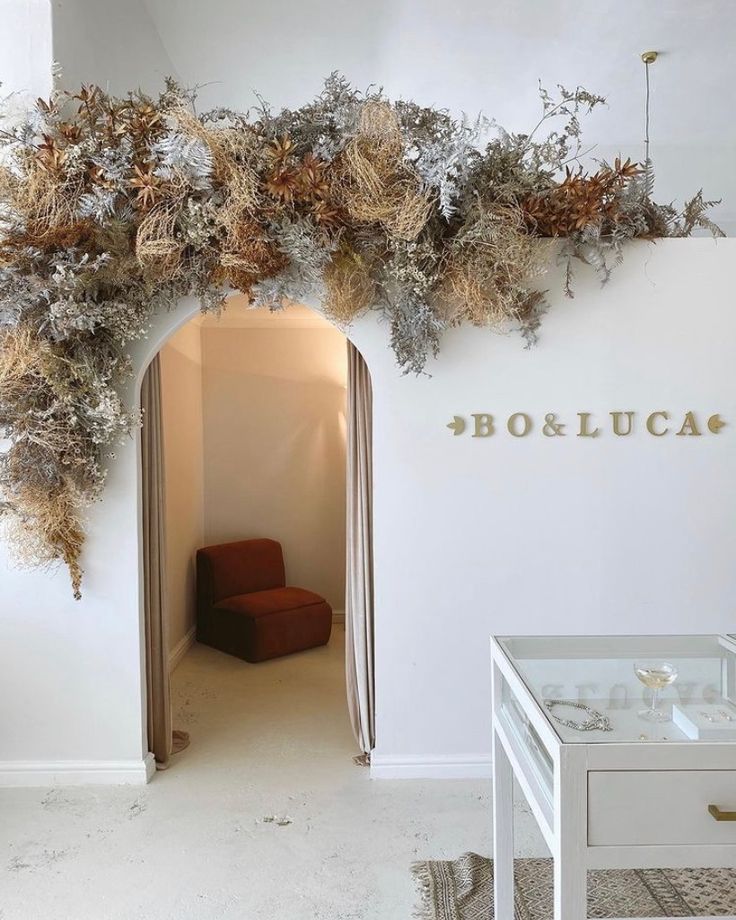 a room with a chair and some plants on the wall above it that reads booeluca