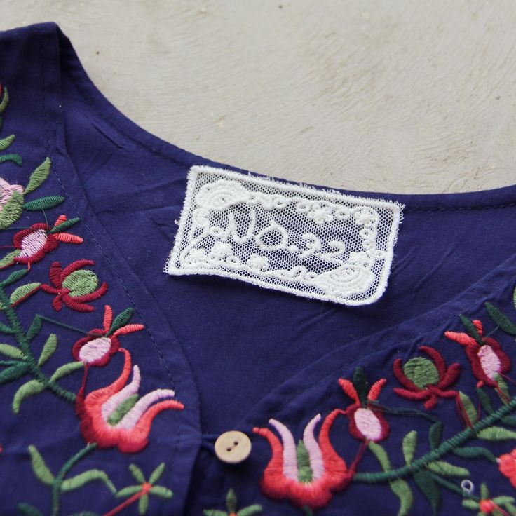 A top seller for your boutique! Gorgeous embroidered details adorn this bohemian tunic dress. Designed with a navy base, v-neck front, short sleeves, and embroidered details throughout. Easy fit for a breezy look. Perfect paired with sandals for an effortless chic summer outfit. One size for small, medium, & large. Custom made to order. Please allow 2 weeks for production. Color: Navy & multi 100% Cotton Imported Hand Wash Cold One size for S,M, & L Bust 37 Waist 38 Hips 39 Length 33 Roses Dress, Bohemian Tunics, Navy Base, Chic Summer Outfits, Embroidered Details, Wholesale Dress, Rose Dress, Wild Roses, Effortless Chic