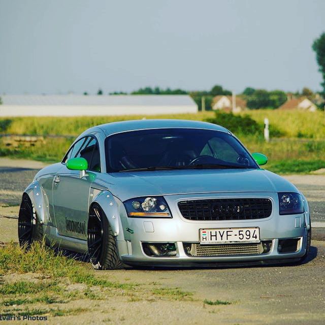 a silver car parked on the side of a road next to a grass covered field