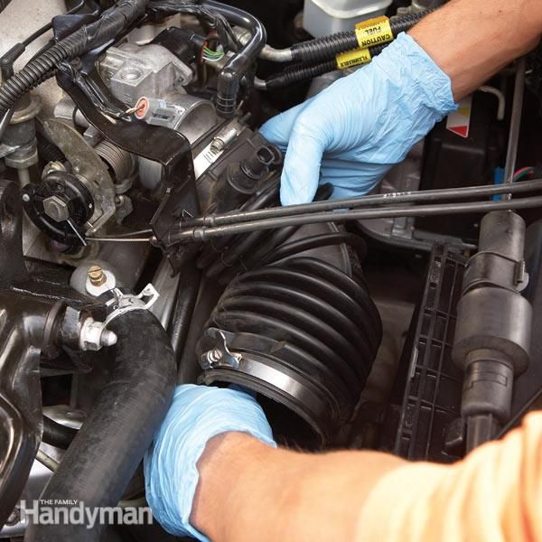 a man is working on an engine in his car with gloves and blue rubber gloves