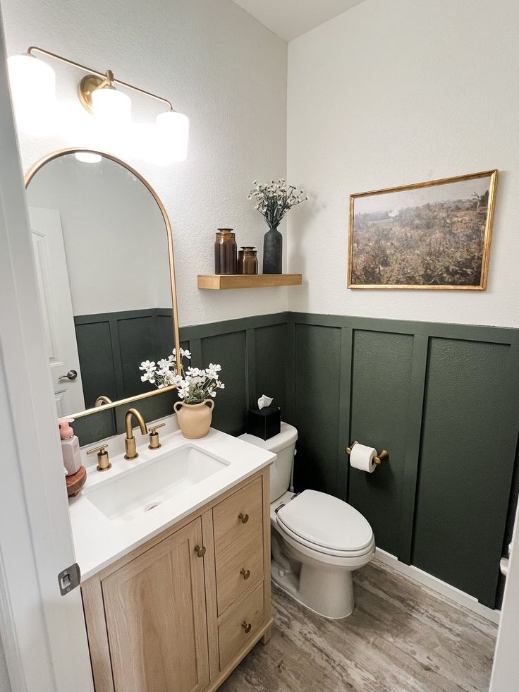 a white toilet sitting next to a sink in a bathroom under a large mirror above it