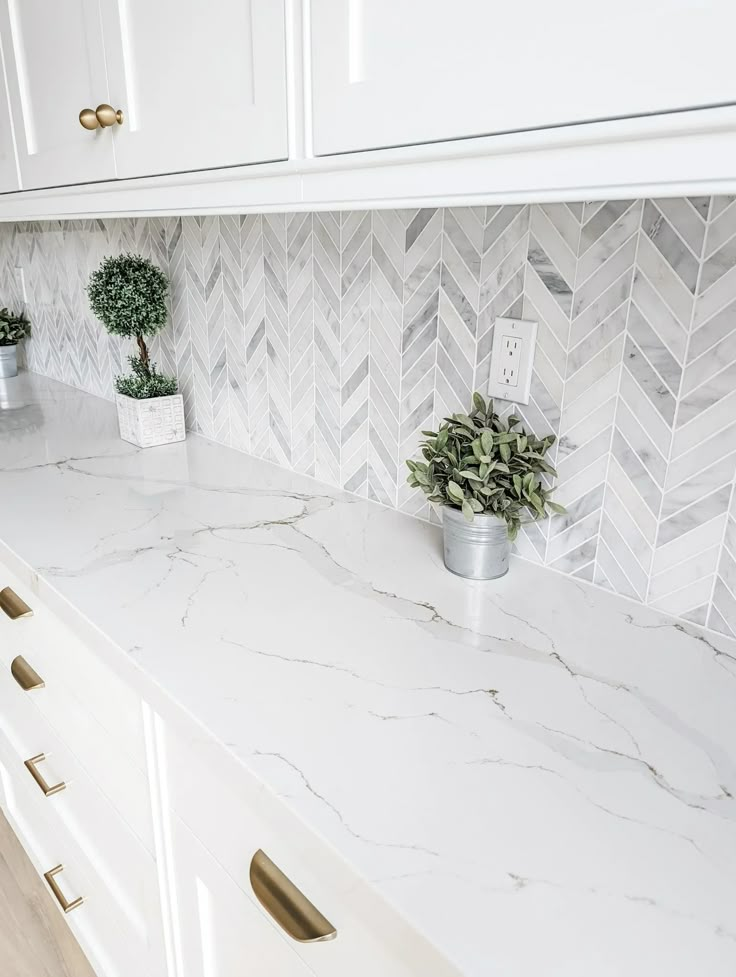 a white kitchen with marble counter tops and gold handles