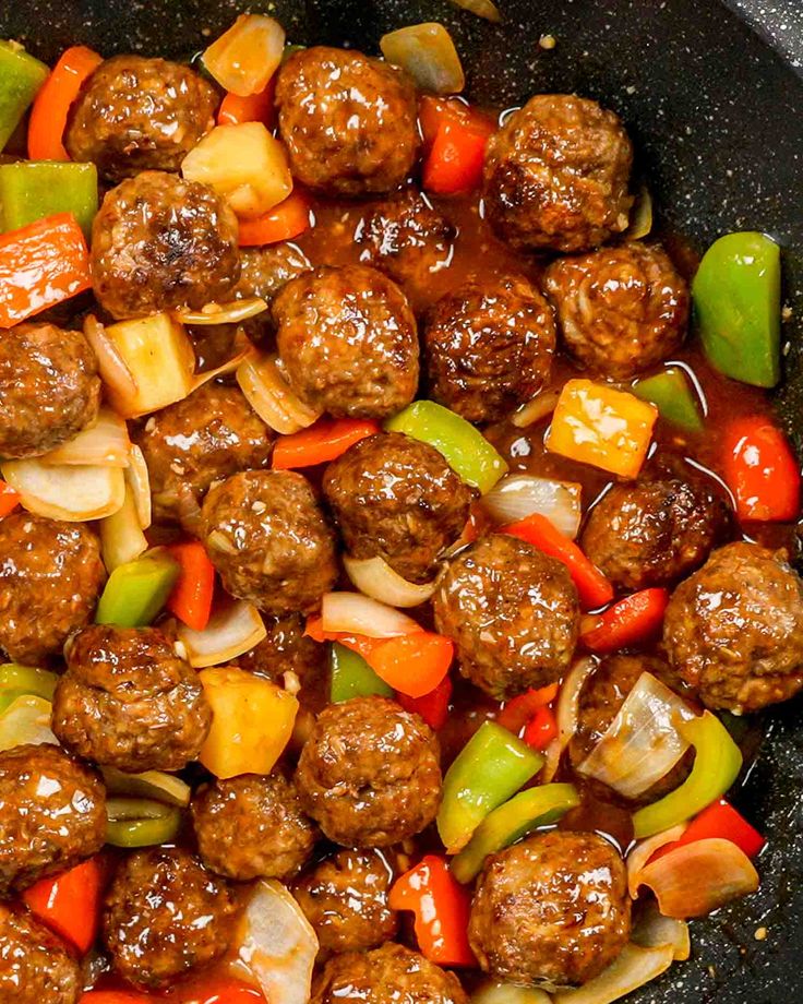 meatballs and vegetables are being cooked in a skillet