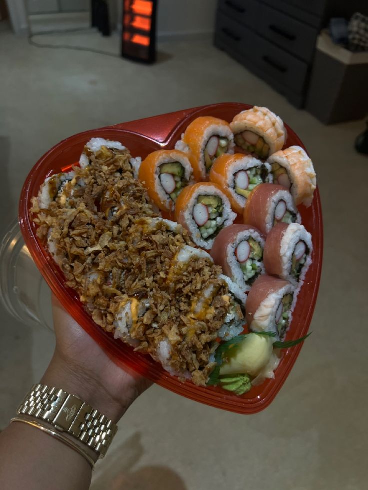 sushi platter being held up in the air by someone's hand with food on it