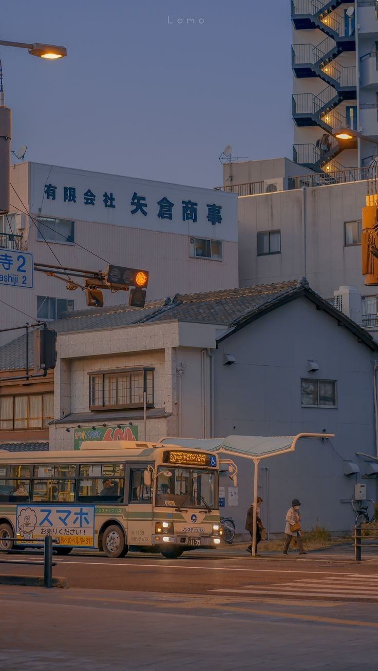 two buses are parked on the side of the road in front of an apartment building