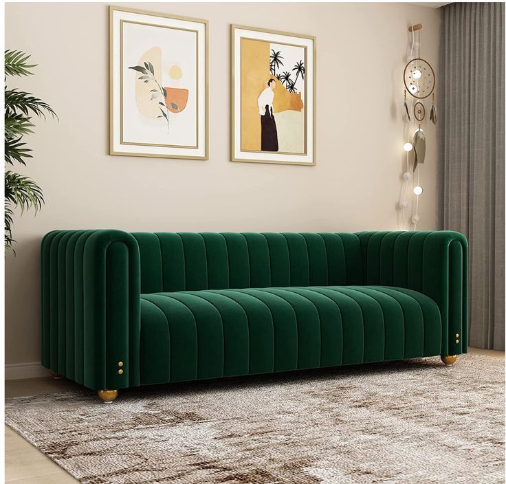 a green velvet couch sitting in front of two pictures on the wall next to a rug