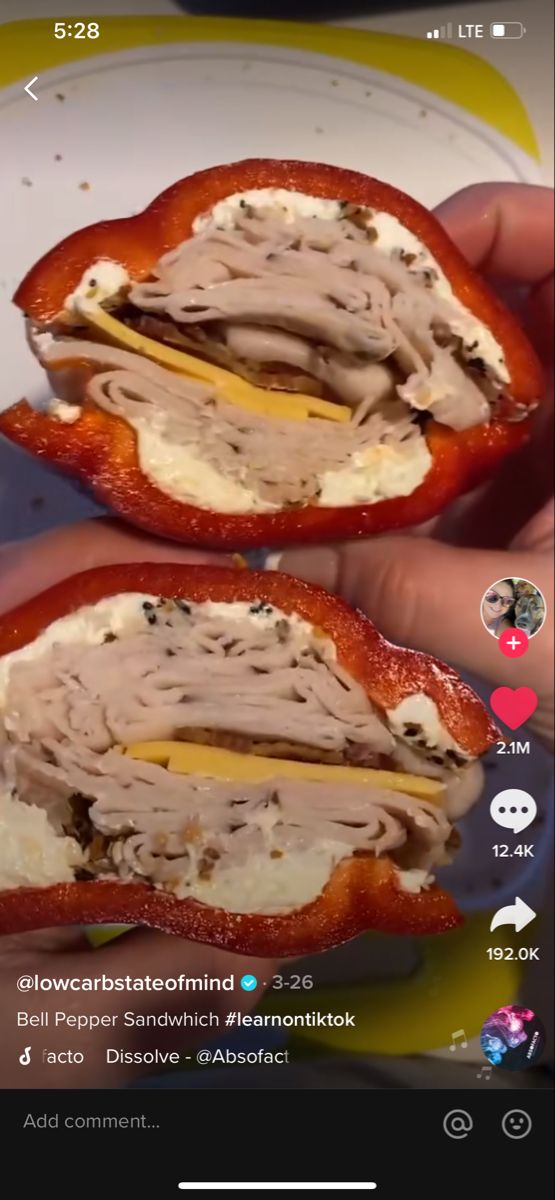 two halves of a sandwich with meat and cheese on it, being held by someone's hand