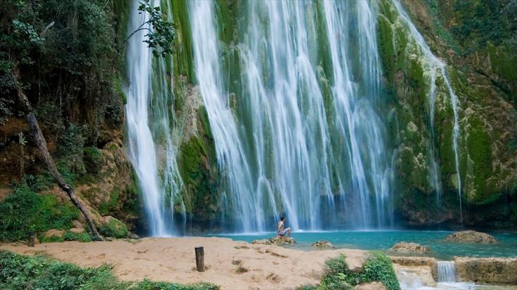 a man standing in front of a waterfall with water cascading down it's sides