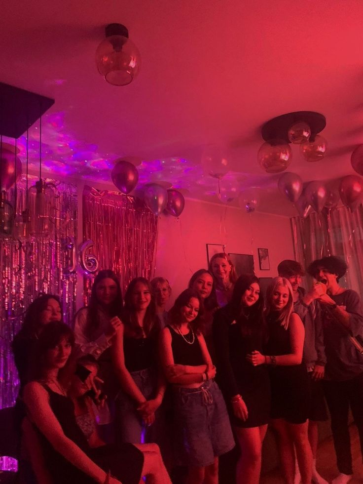 a group of people posing for a photo in a room with balloons and lights hanging from the ceiling