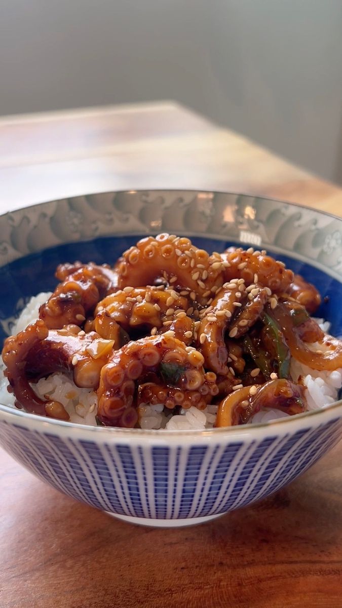 a blue and white bowl filled with food on top of a wooden table