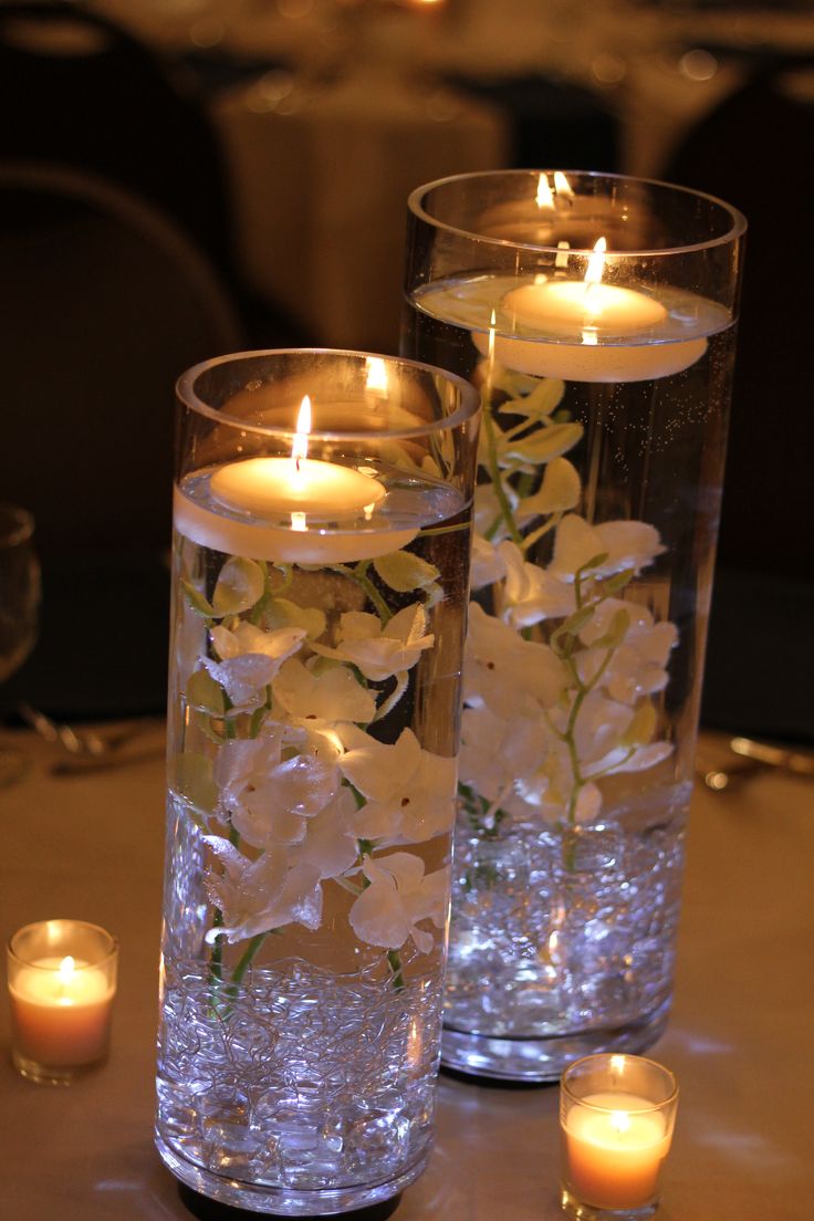 two vases with flowers and candles on a table