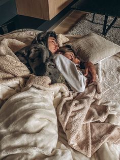 a woman laying on top of a bed under a blanket