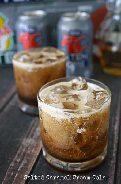 two glasses filled with ice cream sitting on top of a table next to cans of soda