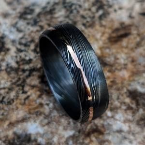 a black and gold wedding ring on top of a rock