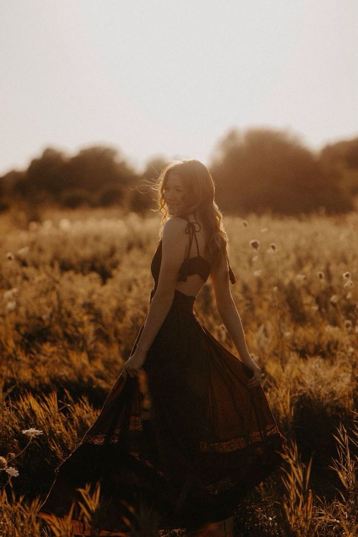 a woman in a long dress standing in a field