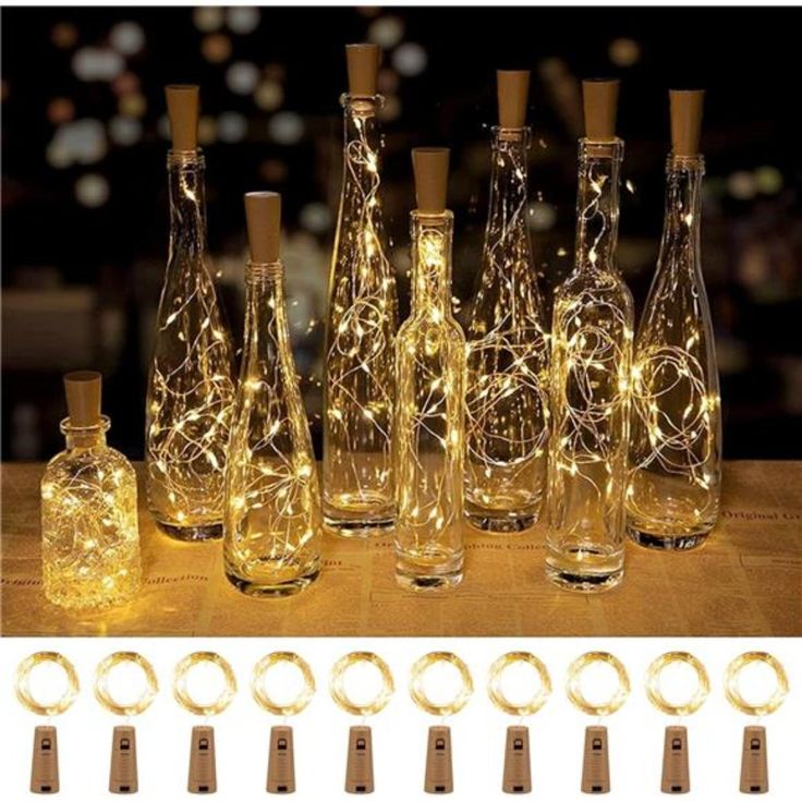 several bottles with lights in them sitting on a table next to each other and some tags