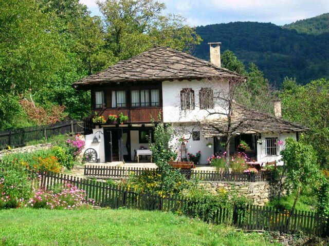 the house is surrounded by greenery and flowers