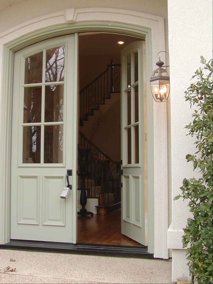 an open door leading into a house with two lights on either side and stairs up to the second floor