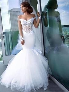 a woman in a white wedding dress leaning against a glass wall with her hand on the door