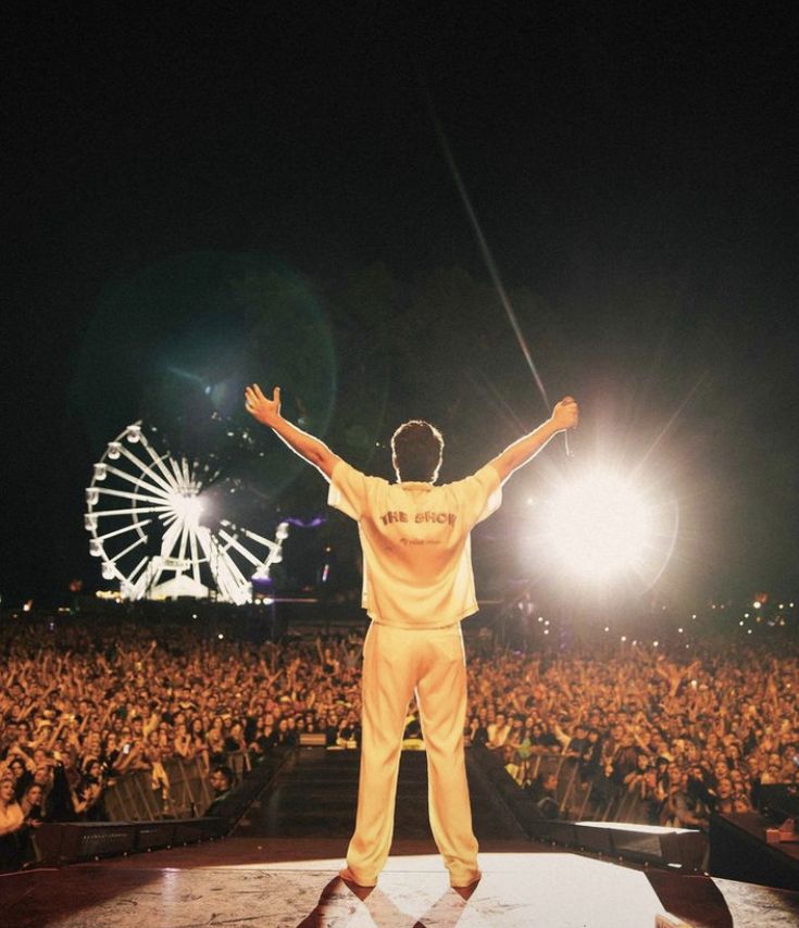 a man standing on top of a stage with his arms wide open in front of an audience