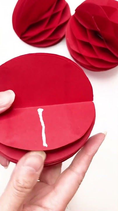 a hand holding a piece of red paper with the word i on it and two flowers in the background