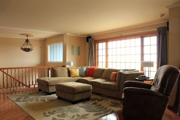 a living room filled with furniture next to a wooden stair case in front of a window