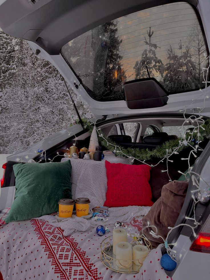 the back end of a car with pillows and blankets on it's bed in the snow