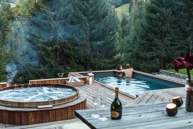 a hot tub sitting on top of a wooden deck next to a lush green forest