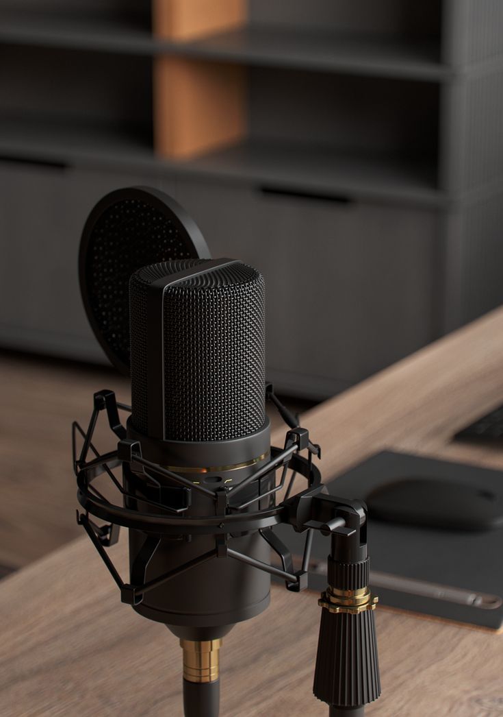 a black microphone sitting on top of a wooden table next to a laptop and mouse