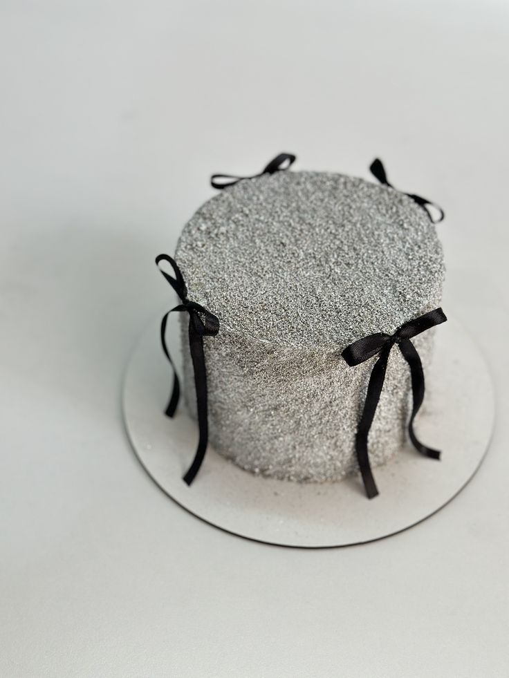 a cake that is sitting on a plate with black ribbon around the top and bottom