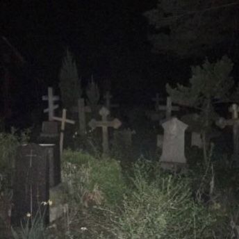 a cemetery at night with tombstones in the grass