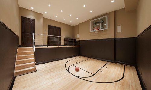 an indoor basketball court with stairs and hard wood flooring in a home gym area