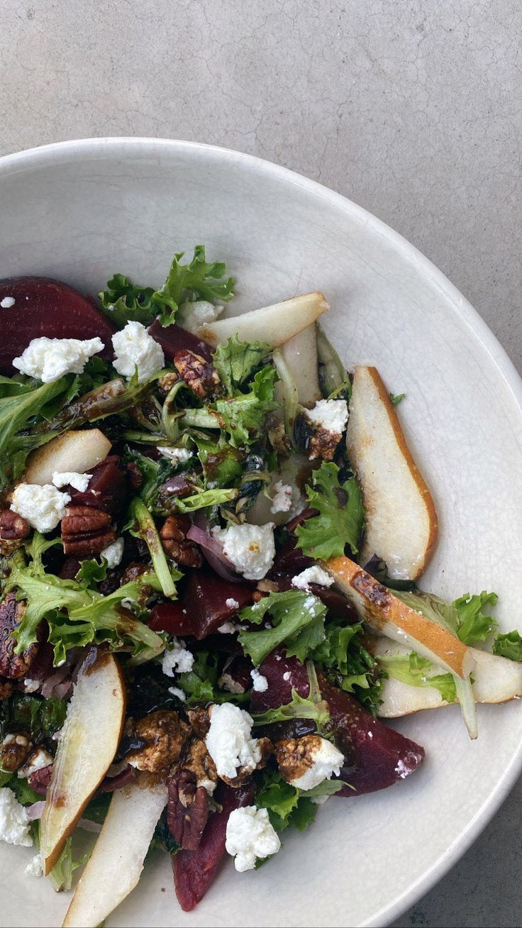 a white bowl filled with salad and apples