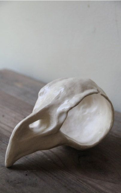 a ceramic bird head sitting on top of a wooden table next to a white wall