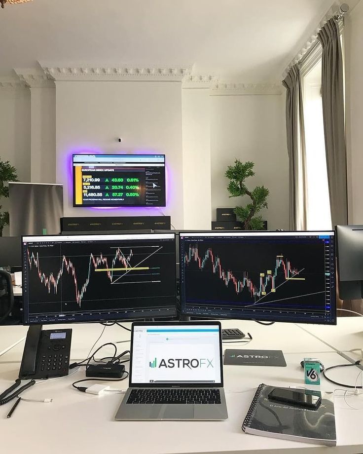 three computer monitors sitting on top of a desk next to laptops and phone devices