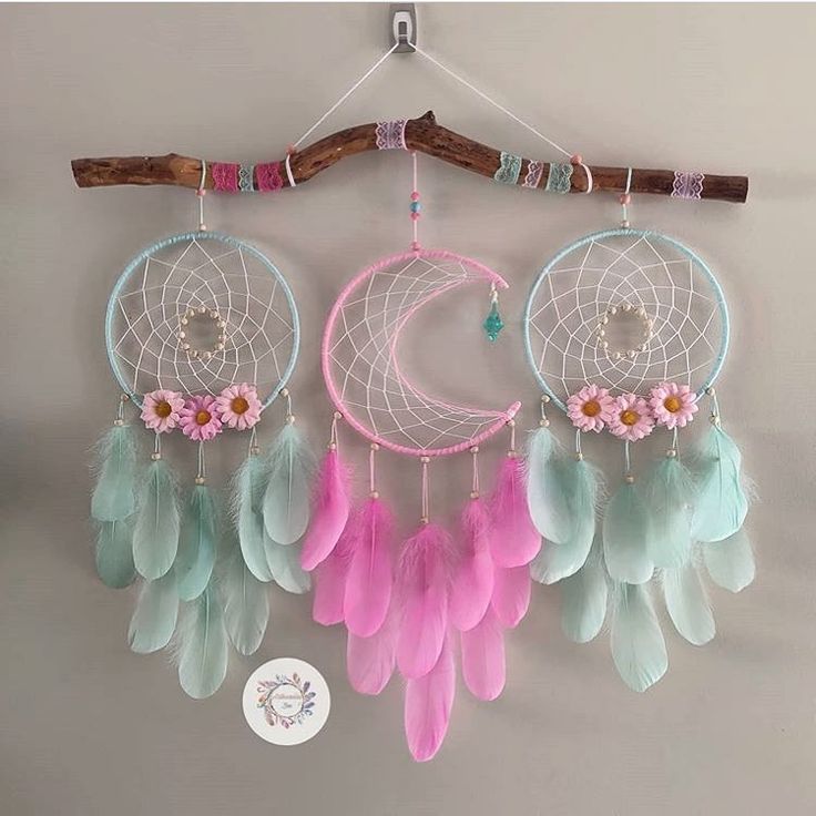 three dream catchers hanging on a wall with pink, blue and green feathers attached to them