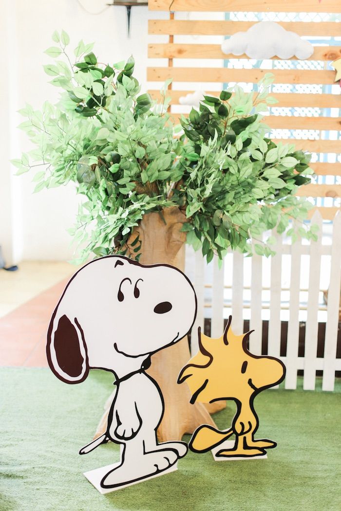 a wooden cutout of a snoopy and his dog next to a potted plant