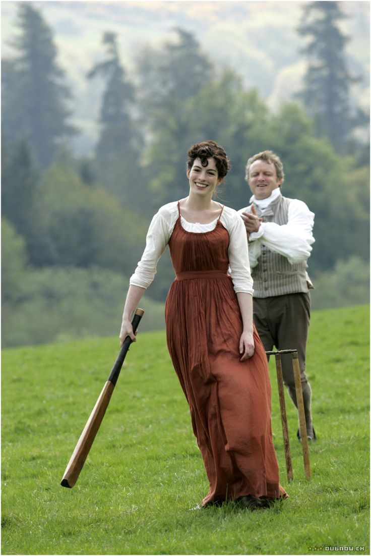 two people standing in a field holding baseball bats