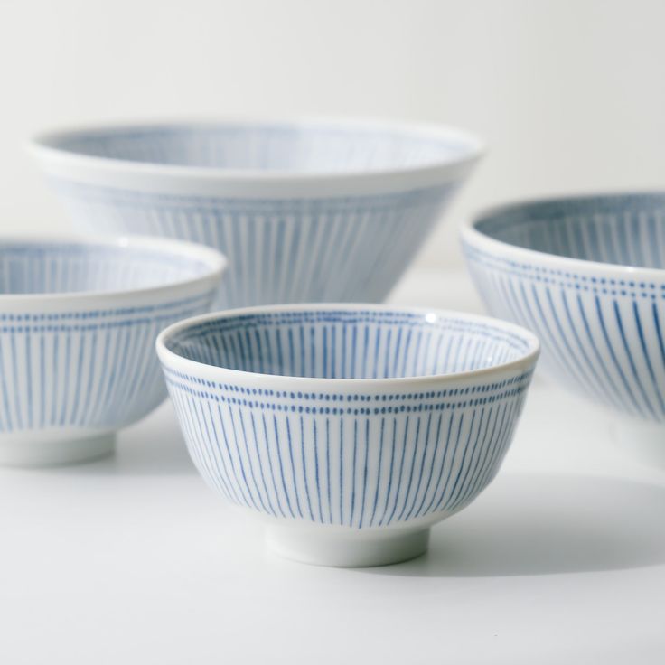 four blue and white bowls sitting on top of a table