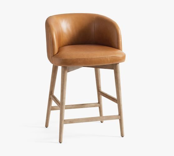 an upholstered stool with a tan leather seat and back rests against a white background