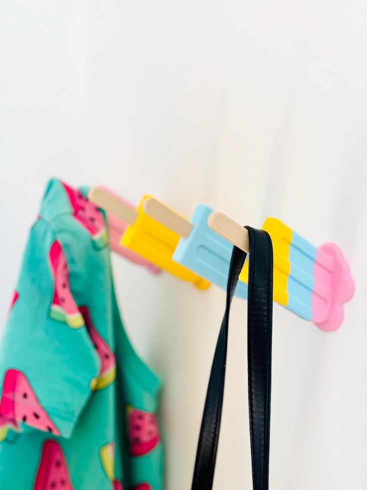 two toothbrushes are hanging on the wall next to a towel rack with watermelon designs