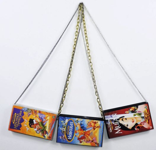 three disney princess purses hanging from chains on a white wall in the shape of an arrow