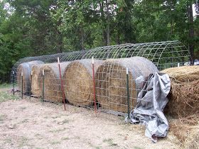 several bales of hay are wrapped in plastic and sitting on the ground next to a wire fence