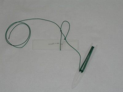 a pen is laying on the ground next to a white card with a green cord