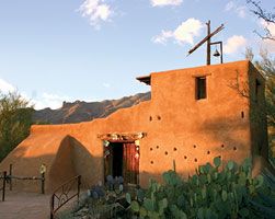 an adobe building with a cross on the roof